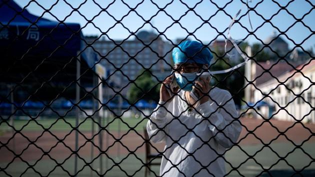 A medical professional speaks on two mobile phones before a mass swab test for people who visited or live near Xinfadi market at Guang’an Sport Centre in Beijing on June 14. The domestic coronavirus outbreak in China had been brought largely under control through strict lockdown restrictions imposed early this year -- but a new cluster has been linked to Xinfadi market in south Beijing now. (Noel Celis / AFP)