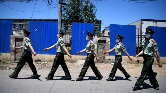 Chinese paramilitary policemen wearing face masks walk past the closed Xinfadi market in Beijing. Several districts of the Chinese capital have set up security checkpoints, closed schools and ordered people to be tested for the novel coronavirus on June 15 after an unexpected spike of cases linked to the biggest wholesale food market in Asia. (Noel Celis / AFP)