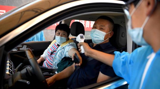 A security personnel checks the temperature of people entering the Xinfadi market on June 14. After nearly two months with no new infections, Beijing officials have reported 79 cases over the past four days, the city’s biggest cluster of infections since February, reported Reuters. (Noel Celis / AFP)