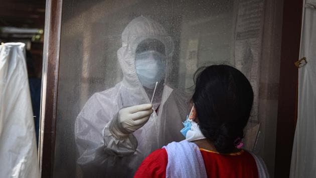 A medical worker wearing PPE coveralls collects a swab sample from a woman to test for COVID-19 infection, in hotel The Exocita Grand, Patel Nagar, in New Delhi.(Sanchit Khanna/HT PHOTO)