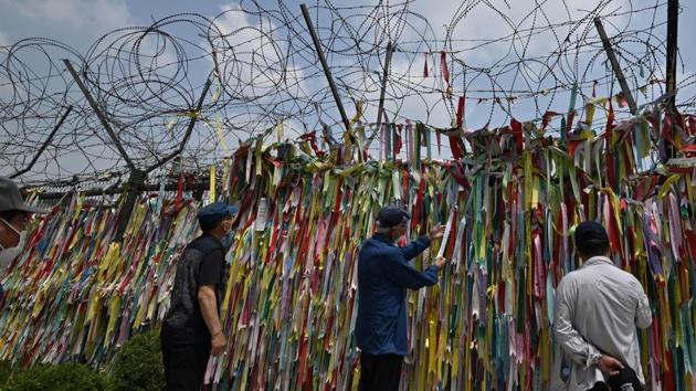 Visitors look at ribbons wishing for peace and reunification of the Korean Peninsula on a military fence at Imjingak peace park near the Demilitarised Zone (DMZ) dividing the two Koreas in the border city of Paju on June 16. (Jung Yeon-je / AFP)