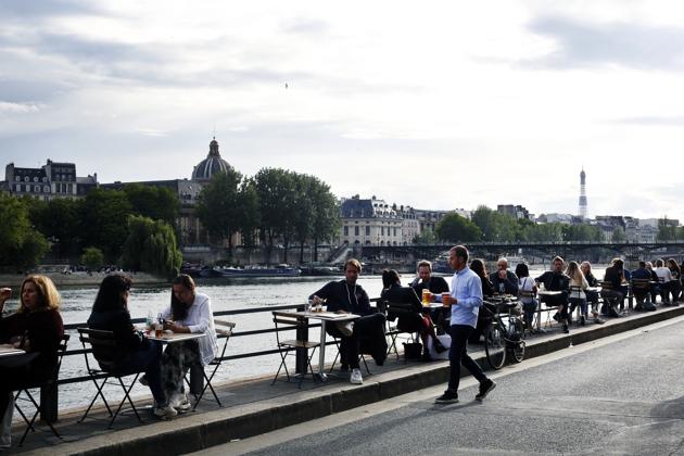 A waiter brings beers to customers in a bar on the Seine river bank, Monday, June 15, 2020 in Paris. Paris is rediscovering itself, as its cafes and restaurants reopen for the first time since the fast-spreading virus forced them to close their doors March 14. Restaurants outside the Paris region opened earlier this month, and Paris cafes were allowed to serve people outside but not open their doors. After three months of losses, some restaurateurs fear it will take a long time for business to come back. (AP Photo/Thibault Camus) (AP)
