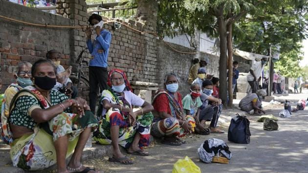Men sit beside lunch boxes placed in queue to receive food during a nationwide lockdown to curb the spread of new coronavirus in Ahmedabad, India.(AP) Men sit beside lunch boxes placed in queue to receive food during a nationwide lockdown to curb the spread of new coronavirus in Ahmedabad, India.(AP)