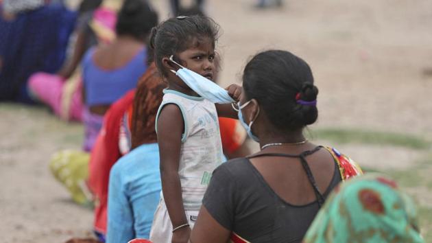 The child of a migrant worker waits to get her temperature checked before being allowed to board a train tomorrow with her family for her hometown, in Jammu, India.(AP)