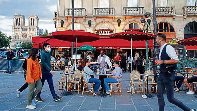 Customers enjoy food at a restaurant with Notre Dame Cathedral in the background in Paris on Monday. (AP) Customers enjoy food at a restaurant with Notre Dame Cathedral in the background in Paris on Monday. (AP)