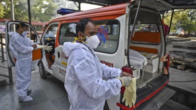 Relatives and medical workers put on PPE coveralls ahead of the cremation of a person who died of the coronavirus, at Nigambodh Ghat in New Delhi.(Biplov Bhuyan/HT PHOTO) Relatives and medical workers put on PPE coveralls ahead of the cremation of a person who died of the coronavirus, at Nigambodh Ghat in New Delhi.(Biplov Bhuyan/HT PHOTO)