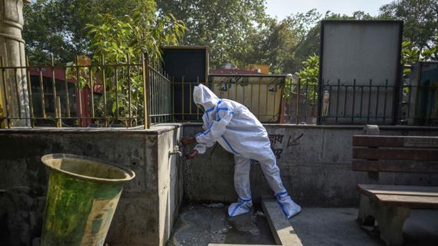 A person in PPE coveralls washes hands ahead of the cremation of a person who died of the coronavirus, at Nigambodh Ghat in New Delhi. (Biplov Bhuyan/HT PHOTO) A person in PPE coveralls washes hands ahead of the cremation of a person who died of the coronavirus, at Nigambodh Ghat in New Delhi. (Biplov Bhuyan/HT PHOTO)