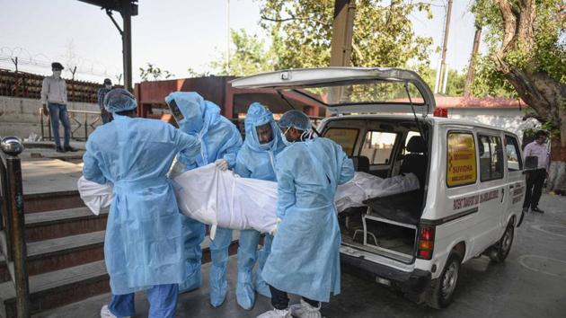 File photo: Relatives and medical workers in PPE coveralls transfer the body of a person who died of the coronavirus from an ambulance, at Nigambodh Ghat in New Delhi. (Biplov Bhuyan/HT PHOTO) File photo: Relatives and medical workers in PPE coveralls transfer the body of a person who died of the coronavirus from an ambulance, at Nigambodh Ghat in New Delhi. (Biplov Bhuyan/HT PHOTO)