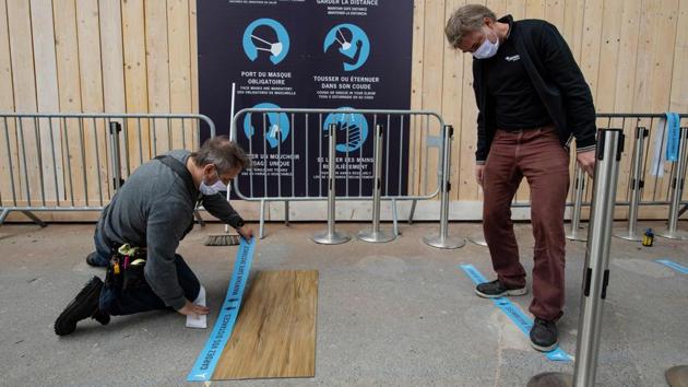 Employees install safety distance signs along the waiting line to the Eiffel Tower on June 15. “To attract people, the most important thing is that security measures are taken, and that’s why we’re promoting safe distances,” Patrick Branco Ruivo, director of Tour Eiffel told Reuters. (Bertrand Guay / AFP) 