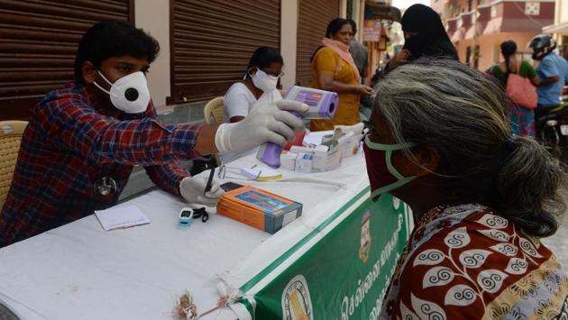 A doctor (L) thermal screens a woman during health checks at a mobile clinic in Chennai on June 16. The decision for extending the lockdown came just days after the state government told the Madras High Court that there would be no lockdown and threatened criminal action against people spreading such rumours. (Arun Sankar / AFP) 