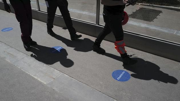 Tour Eiffel workers walk along  the access lane during a presentation of the security measures on June 16. Everyone over 11 years old will be required to wear face masks, and crowd control measures will be in place. (Francois Mori / AP) 