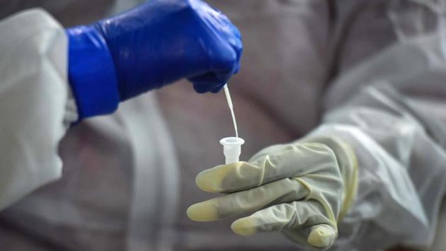 A medic inserts a nasopharyngeal swab into a tube to inactivate the virus before antigen testing at a centre in Nangal Raya on June 18. Apart from containment zones, antigen tests are likely to be rolled out in Delhi’s hospitals within a couple of days. (Sanchit Khanna / HT Photo)