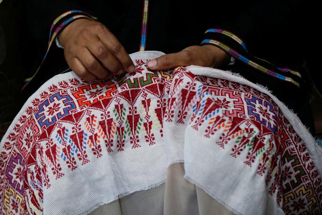Um Zeid, 47 year-old Palestinian refugee woman living in Jordan embroiders a traditional Palestinian dress for customers at Al-Baqaa Palestinian refugee camp. (REUTERS)
