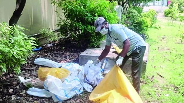 A sanitation worker picking up the used PPE suits that were found thrown near gynaecology ward at civil hospital in Sector 6, Panchkula, on Saturday. (Sant Arora/HT) A sanitation worker picking up the used PPE suits that were found thrown near gynaecology ward at civil hospital in Sector 6, Panchkula, on Saturday. (Sant Arora/HT)