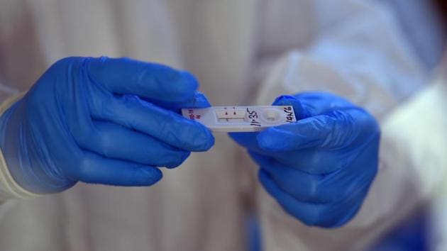 A health worker in an enclosed booth holding a coronavirus Ag antigen test kit, in New Ashok Nagar, New Delhi. (Raj K Raj/HT PHOTO) A health worker in an enclosed booth holding a coronavirus Ag antigen test kit, in New Ashok Nagar, New Delhi. (Raj K Raj/HT PHOTO)
