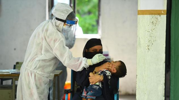 A health worker wearing PPE coveralls collects swab sample from a child at a Covid-19 testing centre, near Turkman Gate, in New Delhi. (Raj K Raj/HT PHOTO) A health worker wearing PPE coveralls collects swab sample from a child at a Covid-19 testing centre, near Turkman Gate, in New Delhi. (Raj K Raj/HT PHOTO)