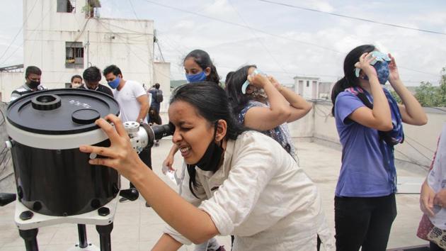 Volunteers of NGO Jyotirvidya Parisanstha watch the annular solar eclipse during a small gathering at Kesariwada in Pune. The coronavirus pandemic has had its impact on the eclipse this year as large gatherings were banned and special events organised at observatories and planetariums were cancelled, reported HT.  (Ravindra Joshi / HT Photo ) 