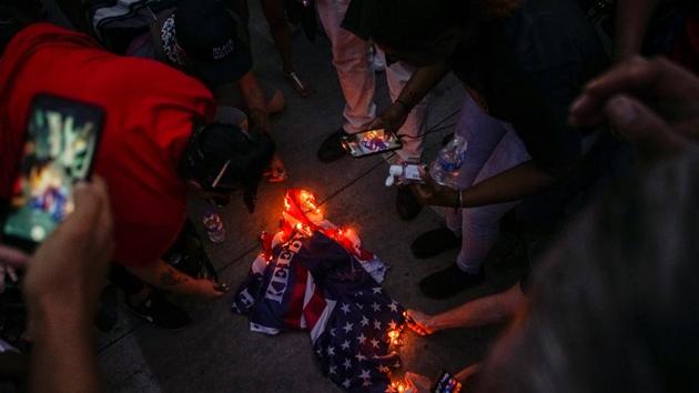 People burn a Trump flag at the protest against racial injustice near the site of a rally by US President Donald Trump in Tulsa, Oklahoma.(Reuters Photo)