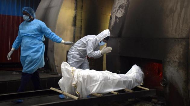 A relative pays their respects to a person who died of Covid-19 before their cremation at Nigambodh Ghat in New Delhi on June 22. The national capital reported 62,655 infections and 2,233 Covid-19 fatalities exiting June 22. The number of new cases saw a slight dip yesterday at 2,909 after an all-time high of 3,630 two days prior. (Sonu Mehta / HT Photo)