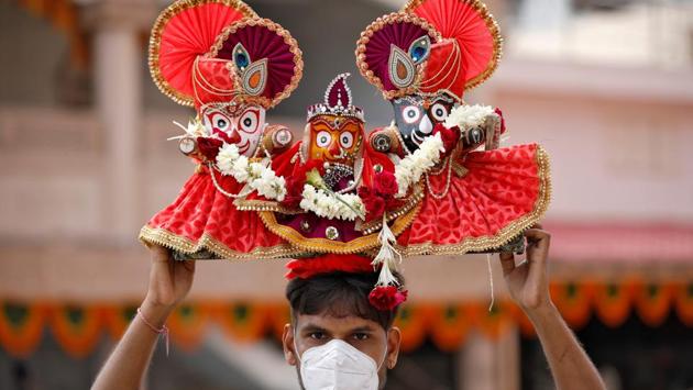 A Hindu devotee, wearing a protective face mask, carries idols of Hindu Lord Jagannath, his sister Subadhra and brother Balabhadra, as he arrives to attend the annual Rath Yatra, or chariot procession, amidst the coronavirus disease (COVID-19) outbreak, in Ahmedabad, India on Tuesday, June 23, 2020. (REUTERS) 