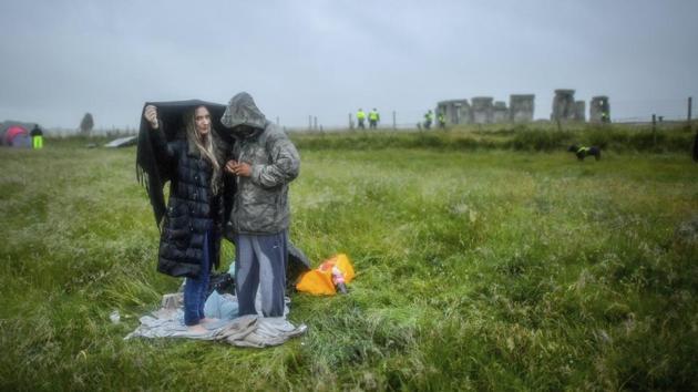 People shield from the rain next to the closed Stonehenge as people gather to celebrate the Summer Solstice, the longest day of the year, near Salisbury, England, Sunday June 21, 2020. (Ben Birchall/PA via AP) People shield from the rain next to the closed Stonehenge as people gather to celebrate the Summer Solstice, the longest day of the year, near Salisbury, England, Sunday June 21, 2020. (Ben Birchall/PA via AP)