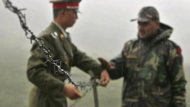 Chinese soldier and an Indian soldier put into place a barbed wire fence removed temporarily for Chinese officials to cross back to their country at Nathula Pass, in northeastern Indian state of Sikkim.(AP)