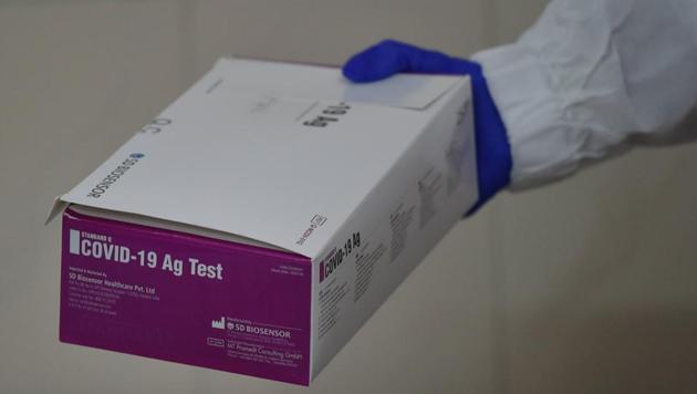 A health technician passes a box containting Covid-19 rapid antigen kits.(PTI)