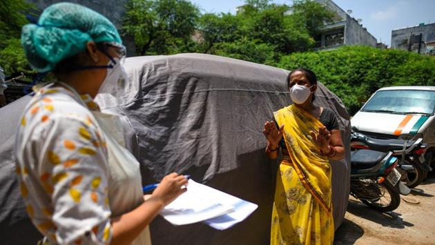 A health worker (L) guides a person who tested positive for Covid-19 regarding further action in New Delhi on June 22. Authorities in Delhi have decided to ramp up containment and tracing efforts, intensify social distancing and surveillance, and inclusion of epidemiologists at the district level to augment existing health care efforts. (Amal KS / HT Photo)