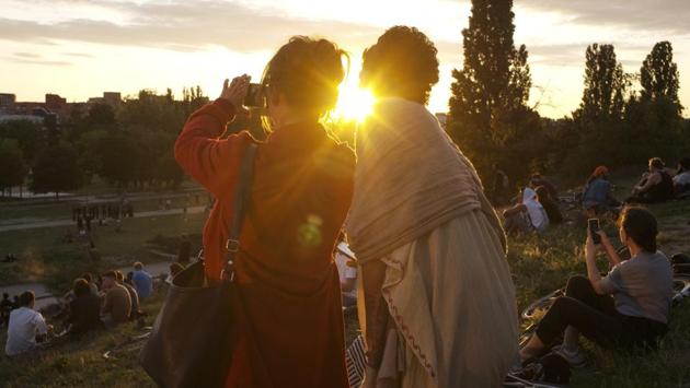 Two women take photos as the sun sets on Summer Solstice, the longest day of the year at the public park Mauerpark in Berlin, Germany, Sunday, June 21, 2020. (AP Photo/Markus Schreiber) Two women take photos as the sun sets on Summer Solstice, the longest day of the year at the public park Mauerpark in Berlin, Germany, Sunday, June 21, 2020. (AP Photo/Markus Schreiber)