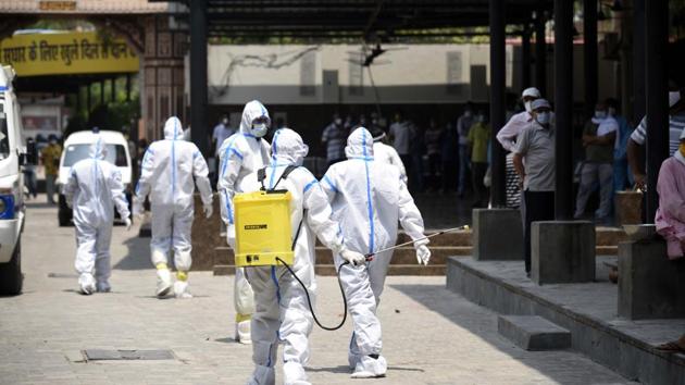A Municipal Corporation of Gururgam (MCG) health workers wearing Personal Protective Equipment (PPE) sanitizes the premises during the cremation of a person who died of Covid-19 at the Madan Puri Cremation Ground near Basai road Chowk, in Gurugram. (Parveen Kumar/Hindustan Times)) A Municipal Corporation of Gururgam (MCG) health workers wearing Personal Protective Equipment (PPE) sanitizes the premises during the cremation of a person who died of Covid-19 at the Madan Puri Cremation Ground near Basai road Chowk, in Gurugram. (Parveen Kumar/Hindustan Times))