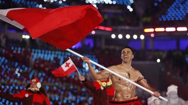 FILE - In this Feb. 9, 2018, file photo, Peta Taufatofua carries a flag of Tonga during the opening ceremony of the 2018 Winter Olympics in Pyeongchang, South Korea, Friday, Feb. 9, 2018. Taufatofua decided to leave his shirt on Tuesday, June 23, 2020 when he led a group of 23 fellow Olympians in a home workout video to help celebrate Olympic Day across 20 time zones. (AP Photo/Jae C. Hong, File)(AP)