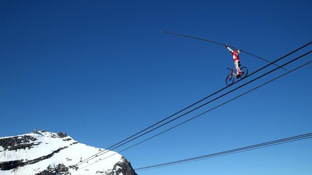 Freddy Nock balances on a bicycle on the cable of the Glacier 3000 cable car during the Airshow in Les Diablerets on June 23. More than 31,000 people have tested positive for the virus and 1,680 have died of COVID-19 in the country so far, according to a report by Reuters. (Denis Balibouse / REUTERS)