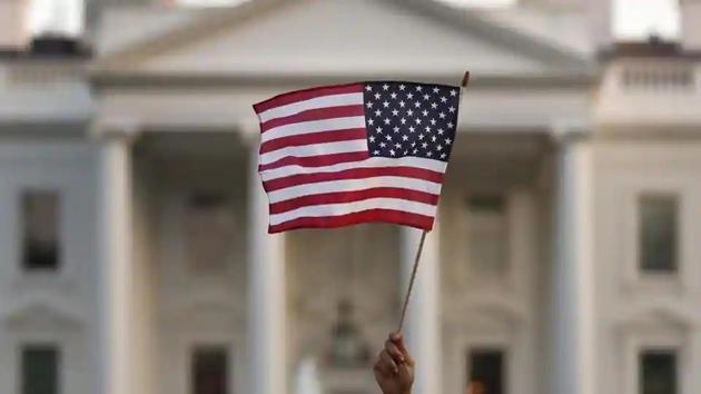 A flag is waved outside the White House in Washington. The Trump administration is extending a temporary ban on green cards issued outside the United States until the end of 2020 and adding many temporary work visas to the freeze. (AP File Photo) A flag is waved outside the White House in Washington. The Trump administration is extending a temporary ban on green cards issued outside the United States until the end of 2020 and adding many temporary work visas to the freeze. (AP File Photo)