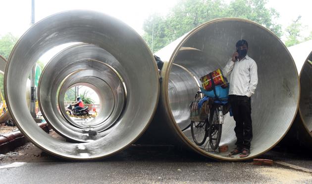 A man takes shelter inside a pipe at a construction site after a sudden rain shower in New Delhi. Monsoon will however, only be officially be declared by the MeT department tomorrow based on the rainfall received between the 24 hour period beginning 8:30 am on June 24. (Mohd Zakir / HT Photo)