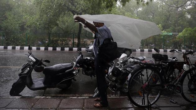 A man spreads a tarpaulin sheet to protect himself from the rain shower in New Delhi. Conditions are also said to be turning favourable for the advance of south-west monsoon into remaining parts of Gujarat, Madhya Pradesh, Uttar Pradesh and Chandigarh in the next 48 hours. (ANI)