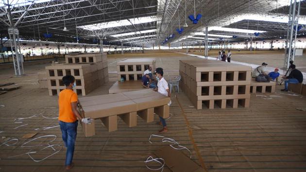 Beds being assembled and placed in the facility. Every patient being housed here will have basic amenities such as a stool, a chair, a small plastic cupboard, a dustbin and utensils, and will be given a toiletry kit. Their beds, considering the numbers will either be foldable iron cots, or those made of cardboard as seen here. (Ajay Aggarwal /HT PHOTO) Beds being assembled and placed in the facility. Every patient being housed here will have basic amenities such as a stool, a chair, a small plastic cupboard, a dustbin and utensils, and will be given a toiletry kit. Their beds, considering the numbers will either be foldable iron cots, or those made of cardboard as seen here. (Ajay Aggarwal /HT PHOTO)