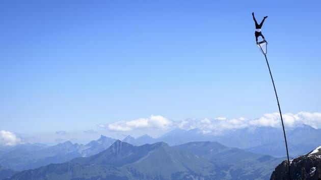 Acrobatic artist Ramon Kathriner performs on a pole with Swiss Alps in the background during the Glacier 3000 Air Show to draw attention to the dramatic situation in the event industry due to the coronavirus outbreak in the village Les Diablerets of the municipality Ormont-Dessus, Switzerland, Tuesday, June 23, 2020. (Laurent Gillieron/Keystone via AP)