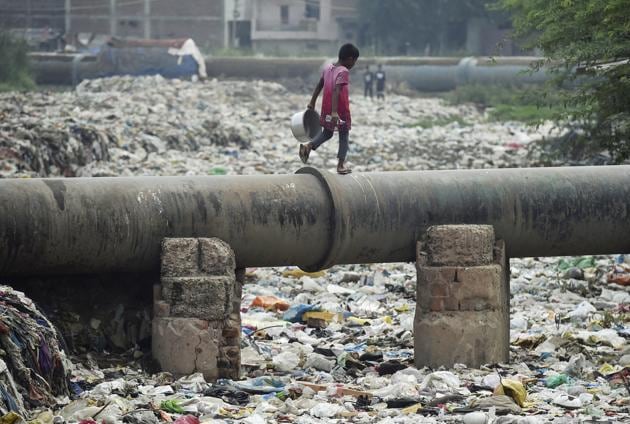 A girl walks on a sewage pipe over the semi-dry drain. (PTI photo for representation) A girl walks on a sewage pipe over the semi-dry drain. (PTI photo for representation)
