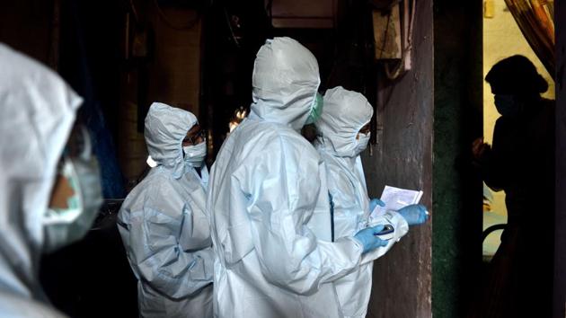 Medical professionals wearing PPE overalls take details from a resident during a door-to-door screening in Dharavi. (Satish Bate / HT Photo)