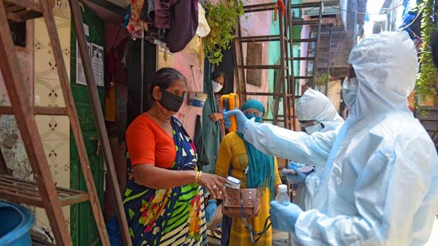 A medical professional wearing PPE coveralls thermal screens a resident in Dharavi. “We have actively followed our model of four Ts – tracing, tracking, testing and treating. Our focus was on treatment and discharge. We took up several other measures like isolating maximum people and door-to-door screening in slums,” Kiran Dighavkar, assistant municipal commissioner of G-North ward (Dharavi), told HT. (Vijayanand Gupta / HT Photo)