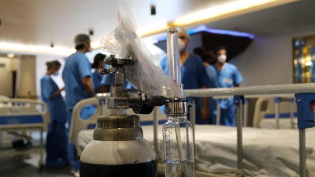 Doctor gather near to an oxygen cylinder in a ward makeshift ward at an emergency Covid-19 care center set up in the Shehnai Banquet Hall at the Lok Nayak Jai Prakash Hospital Annexe in New Delhi on Wednesday.(Bloomberg Photo) Doctor gather near to an oxygen cylinder in a ward makeshift ward at an emergency Covid-19 care center set up in the Shehnai Banquet Hall at the Lok Nayak Jai Prakash Hospital Annexe in New Delhi on Wednesday.(Bloomberg Photo)