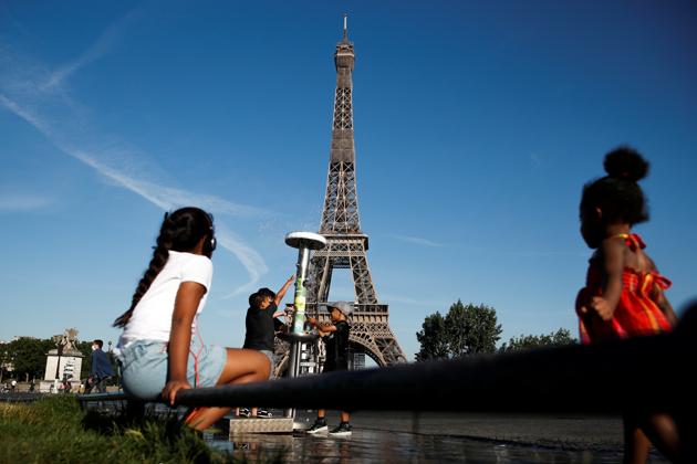 Children cool off in a water fountain near the Eiffel Tower in Paris on June 24. The Parisian landmark welcomed back visitors after the coronavirus outbreak forced Eiffel into its longest period out of action since WWII. (Gonzalo Fuentes / REUTERS)