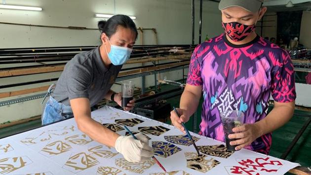 Malaysian textile and fashion designer Mohd Hafiz Drahman (R) and his worker paint customised masks using batik, a traditional Malay design technique at a studio, amid the coronavirus disease (COVID-19) outbreak in Shah Alam, Malaysia June 23, 2020. (REUTERS)