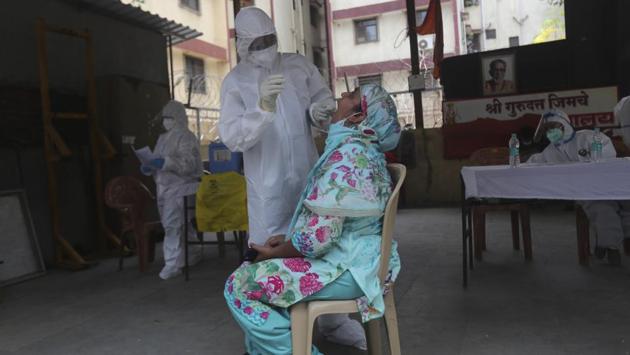 A medical professional collects a swab sample from a woman during a free medical checkup in Dharavi. Around fifty mobile fever clinics in ambulances with a team of medics drive around all day for door-to-door check on residents, detect symptoms or comorbidity, collect swabs from suspects and create general health awareness among the people there, reported IANS. (Rafiq Maqbool / AP)