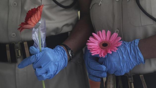 Security personnel hold flowers given to them during a free medical camp in Dharavi. Dharavi’s doubling rate has gone up to 78 days, double the Mumbai average of around 37 days, reported IANS. (Rafiq Maqbool / AP)