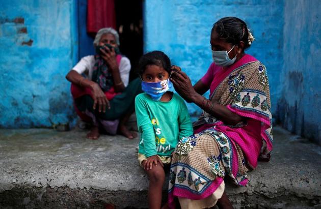 A woman wearing a protective face mask adjusts her daughter's face mask outside their house at a slum area, during an extended nationwide lockdown to slow the spreading of the coronavirus disease (Covid-19), in New Delhi.(REUTERS)