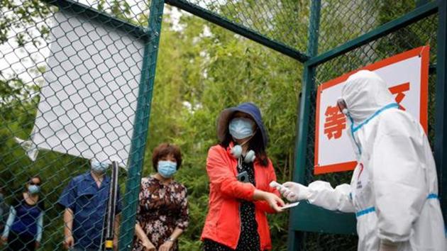 A woman has her body temperature checked as she arrives for a nucleic acid test during a government-organized visit to a testing site in Beijing, China.(REUTERS)