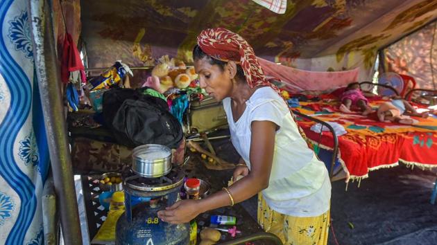 Trapeze artist Anuradha Devi prepares food for her children in her tent at the Rambo Circus. The crew spend their days in their tents, huddled around a television set, on their mobile phones or cooking meals on stoves. Though the team is used to staying in tents, Cyclone Nisarga earlier this month left a trail of destruction, compounding their many problems. (Mitesh Bhuvad / PTI)
