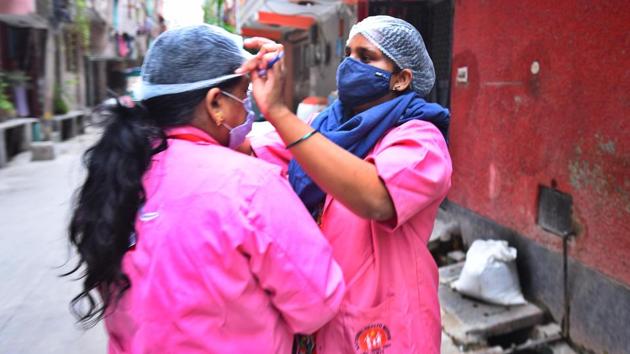 Asha workers during a door-to-door screening survey exercise in Pandav Nagar on June 26. Working on the frontlines, ASHA workers put in long hours in helping the capital manage the outbreak, while conducting surveys, screening patients in home isolation or at testing centres but are paid just Rs 4,000 per month as basic salary. (Raj K Raj / HT Photo)