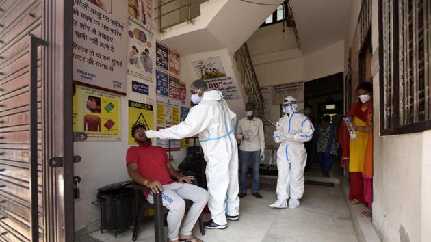 Health workers collect a Covid-19 test sample from a local resident, at Urban Primary Health Centre in Gurugram’s Rajiv Nagar on Saturday. (Praveen Kumar/HT Photo) Health workers collect a Covid-19 test sample from a local resident, at Urban Primary Health Centre in Gurugram’s Rajiv Nagar on Saturday. (Praveen Kumar/HT Photo)